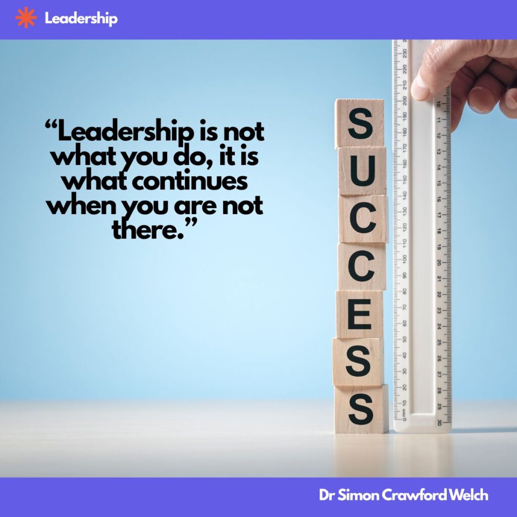 Quote: "Leadership is not what you do, it is what continues when you are not there." By Dr. Simon Crawford Welch. Against a soft sky blue background, six wooden cube blocks are stacked vertically, each face printed with a single black letter that spells the word SUCCESS reading from top to bottom. Beside the stack stands a tall white measuring ruler marked with centimeters and millimeters, held in place by a human hand at the top, as if measuring the exact height of the success column. Measuring legacy rather than presence. The image reframes success as something that can be quantified by what remains standing after a leader steps away, emphasizing the structures, habits, and culture that continue without supervision.