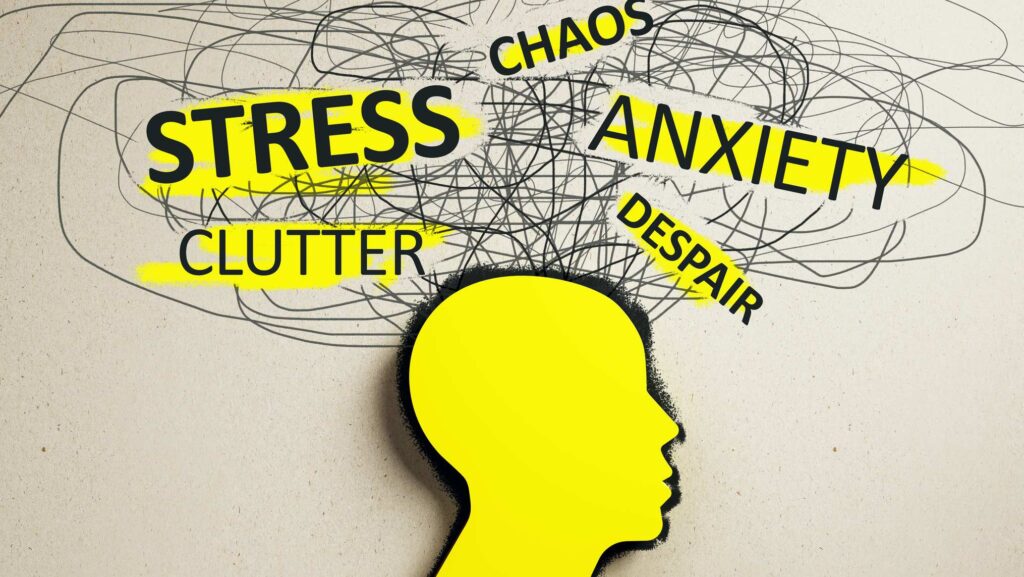 A yellow silhouette of a human head in profile sits at the bottom of a beige, textured paper background, with a dense tangle of scribbled grey lines spilling upward and outward from where the head meets the mind. Overlaid across the scribbles are bold words, several highlighted in yellow, reading STRESS, CLUTTER, CHAOS, ANXIETY, and DESPAIR. The scribbled noise crowding the space above the head visualizes an overloaded inner world, tying the image to the emotional intelligence theme of recognizing internal turmoil before it takes over.