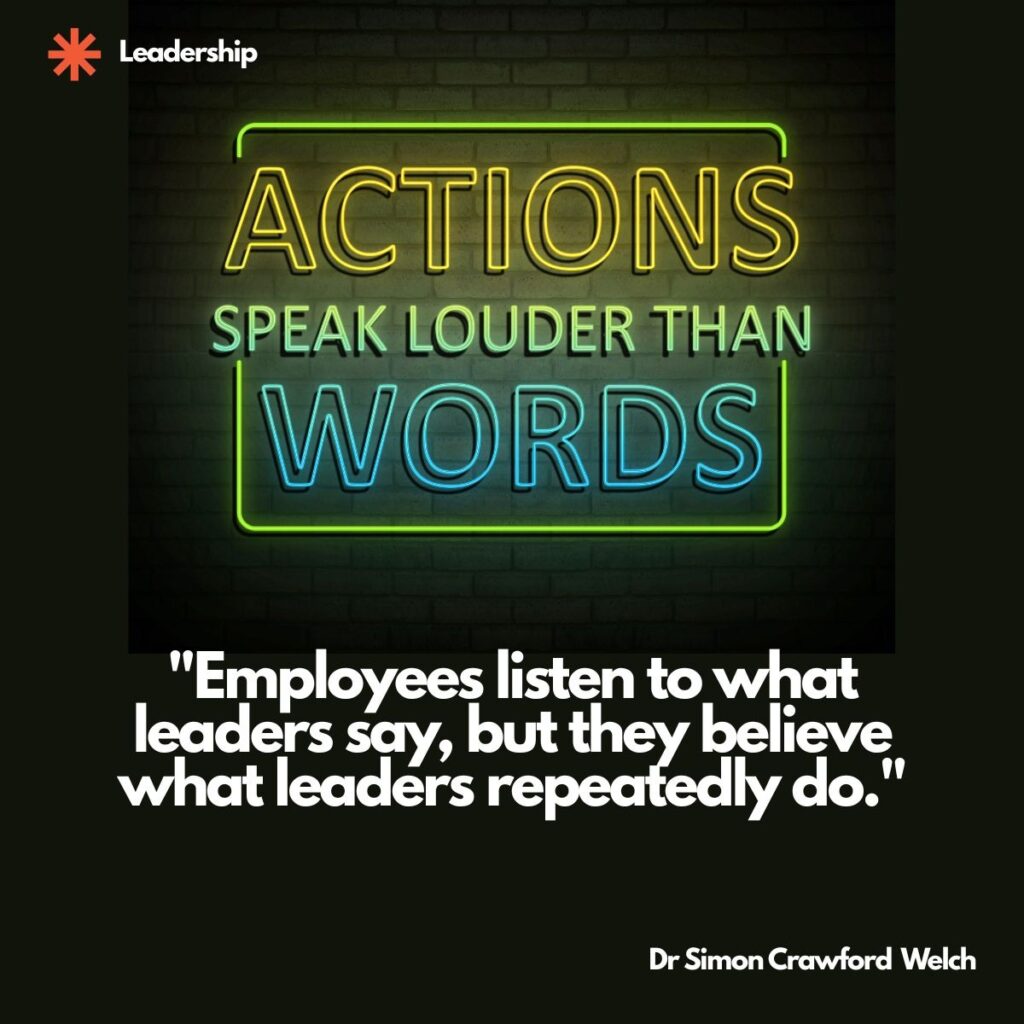 Visual description: Against a dark brick wall, a neon sign glows with the phrase ACTIONS SPEAK LOUDER THAN WORDS, the word ACTIONS in yellow, SPEAK LOUDER THAN in green, and WORDS in blue, all framed by a green neon rectangle. The category label Leadership appears at the top left beside an orange asterisk mark.
Concept: The glowing sign restating a familiar truth about actions sets up the leadership theme of credibility being earned through repeated behavior rather than stated intent.
Quote: "Employees listen to what leaders say, but they believe what leaders repeatedly do."
By Dr Simon Crawford Welch

