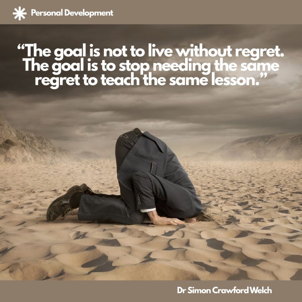 A man in a dark suit kneels in a windswept sandy desert under heavy storm clouds with his head buried in the sand, inside a taupe frame, with a Personal Development label in the top corner. The image represents avoiding the lesson that regret is trying to teach. Quote over the image reads: "The goal is not to live without regret. The goal is to stop needing the same regret to teach the same lesson." By Dr. Simon Crawford Welch.