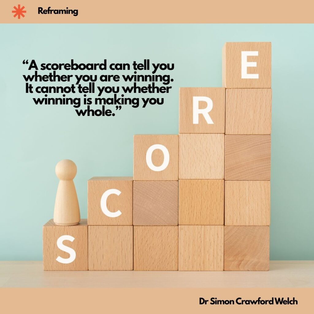 Light wooden blocks stacked like a staircase spell out the word SCORE in white letters, with a small wooden peg figure standing on the bottom step, against a soft mint green wall inside a peach frame, with a Reframing label in the top corner. The image represents chasing the scoreboard and asking whether winning is making you whole. Quote over the image reads: "A scoreboard can tell you whether you are winning. It cannot tell you whether winning is making you whole." By Dr. Simon Crawford Welch.